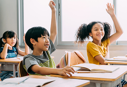 Children raising their hands in classrom