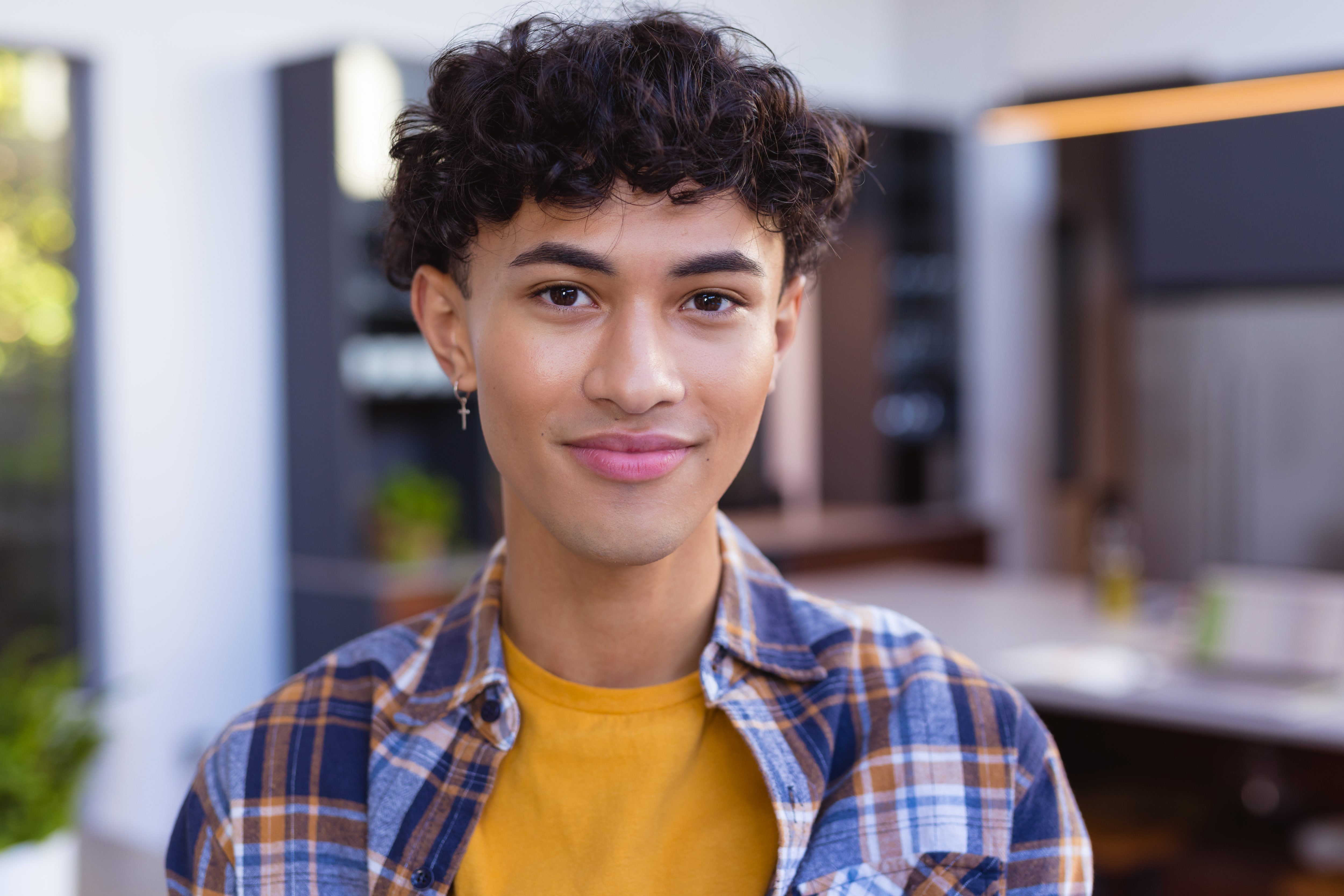 Smiling teenage boy in casual outfit at home, feeling confident