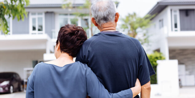 senior couple standing outside looking at their home