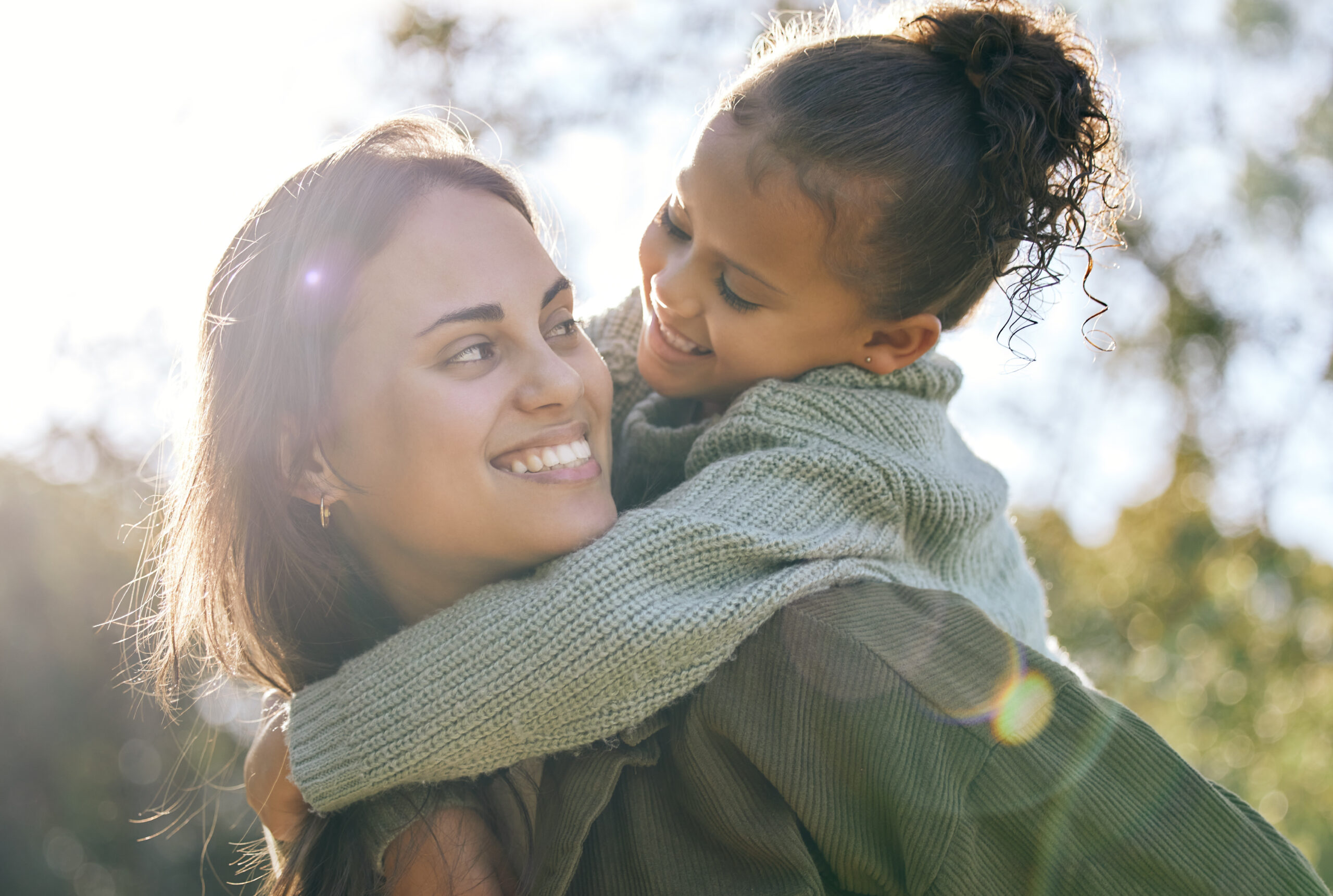 Happy, piggyback and a mother and child in a park for playing, bonding and quality time. Smile, hug and a young mom with a girl kid in nature with love, care and happiness